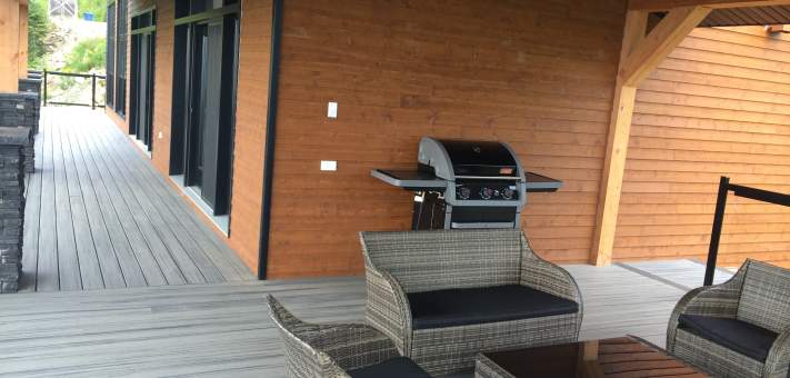 Sitting area and BBQ on covered deck at the Ilaali Chalet of Charlevoix. - Cottage for rent Charlevoix