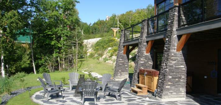 Relaxing area on the lower ground level, recently landscaped, with wood fireplace and SPA at Le Versant du Massif. - Cottage for rent Charlevoix