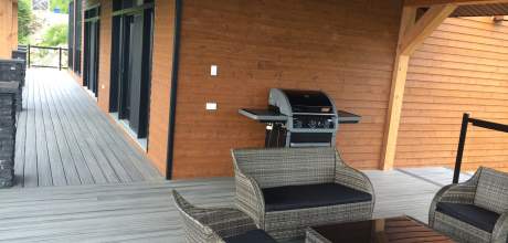 Sitting area and BBQ on covered deck at the Ilaali Chalet of Charlevoix.